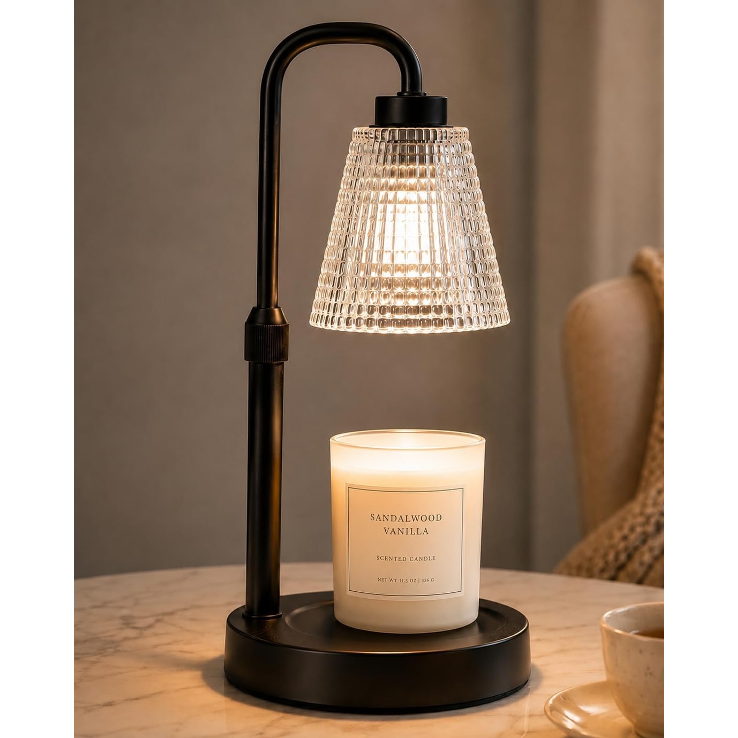 Matt black candle warmer lamp with a fluted glass shade lit above a white jar candle on a marble surface